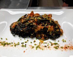 Chitarrina al nero al pesto di datterini e pistacchio di Bronte con riccio di mare e salicornia